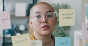 A woman wearing glasses standing in front of post it notes